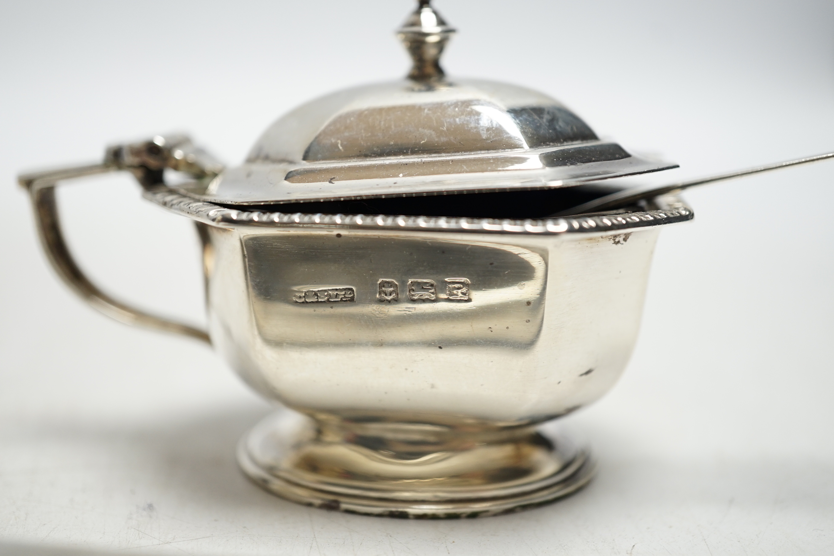 A George VI engine turned silver cigarette case, a silver lidded mustard pot and a small silver cream jug.